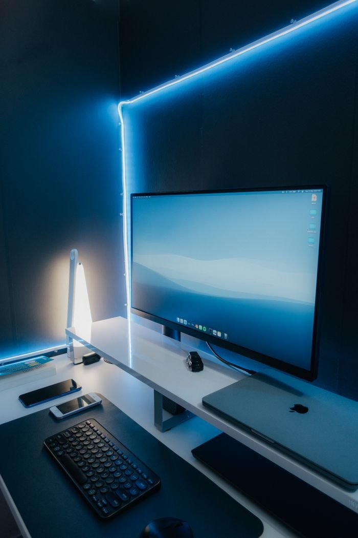 Services A sleek and modern workspace setup featuring a desktop monitor, keyboard, and LED lighting.