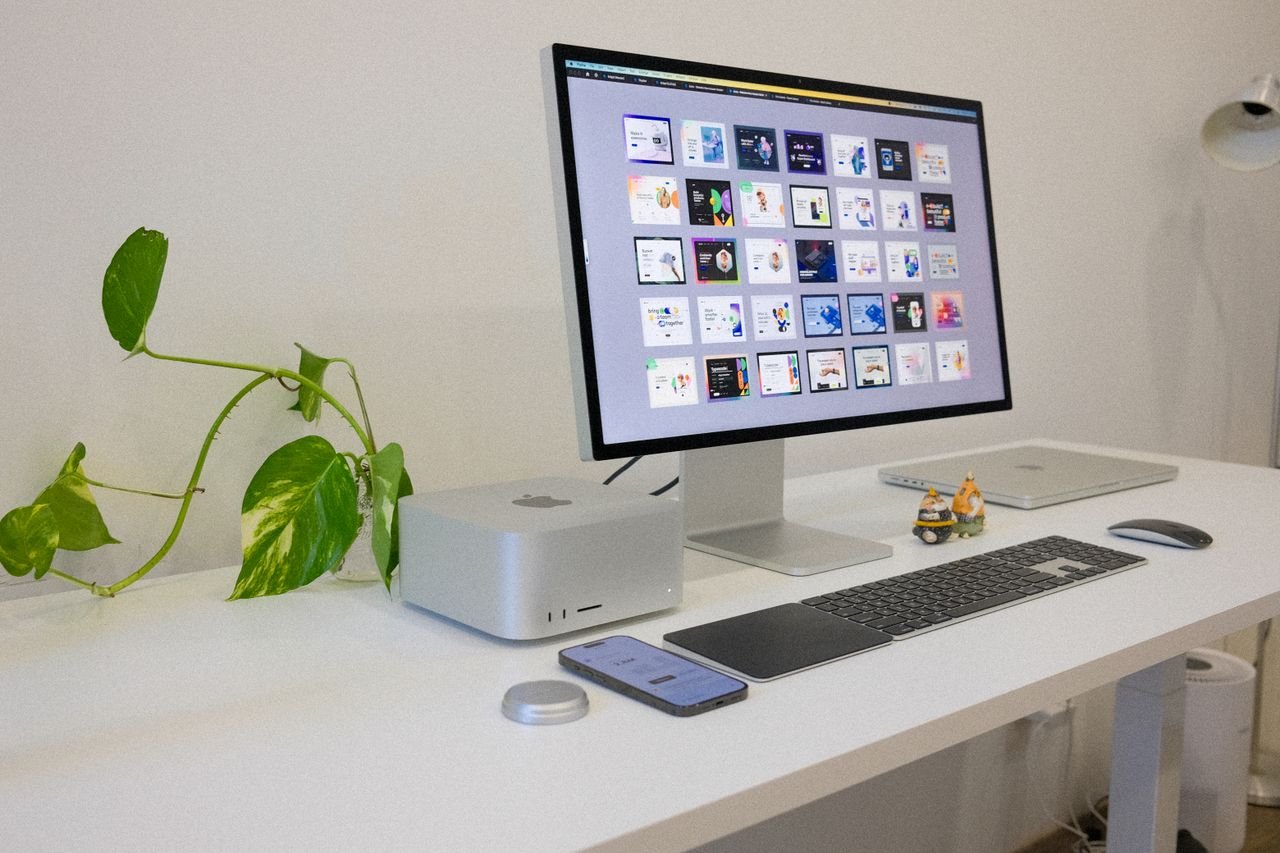 Services A sleek and modern workstation featuring Apple devices and a touch of greenery, ideal for tech enthusiasts.
